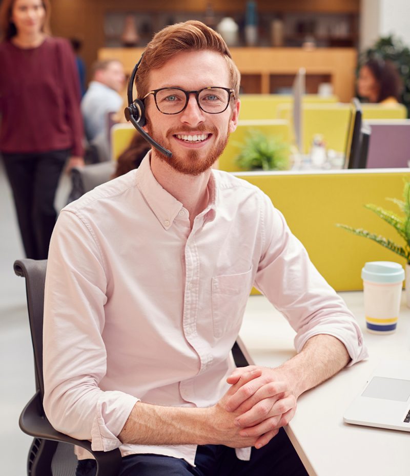 Portrait Of Businessman Wearing Headset Talking To Caller In Cus