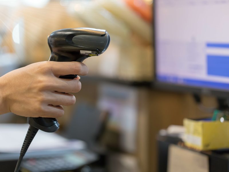 Close up barcode scanner in hand on blurred background,Inspection of goods in the warehouse,The concept of selling products in a supermarket,Spot focus,Copy space.