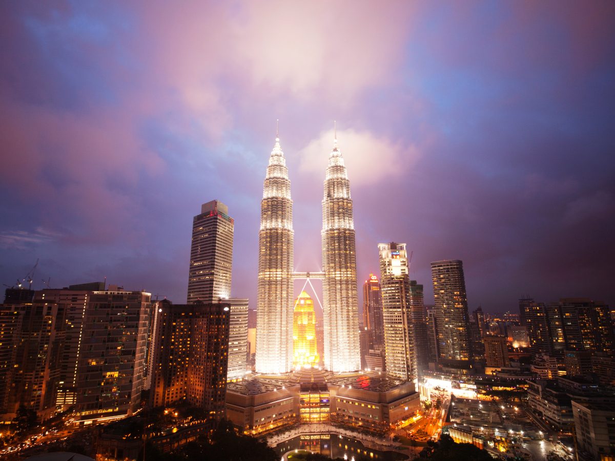 Illuminated PETRONAS Towers against dramatic sky