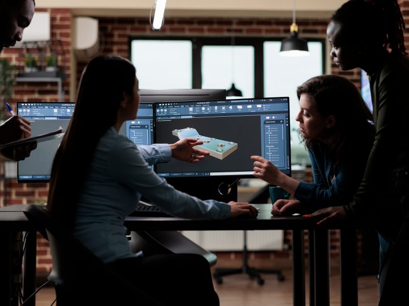 Production department team gathered around 3D artist engineer trying to solve geometry problem.
